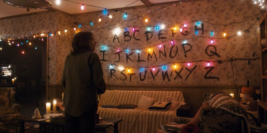 Joyce in front of the alphabet wall with its lit Christmas lights in Stranger Things