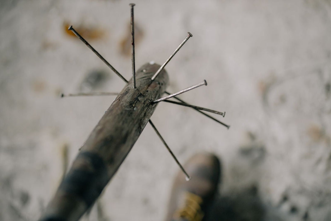 Wooden bat with metal nails, dark handle, light ground
