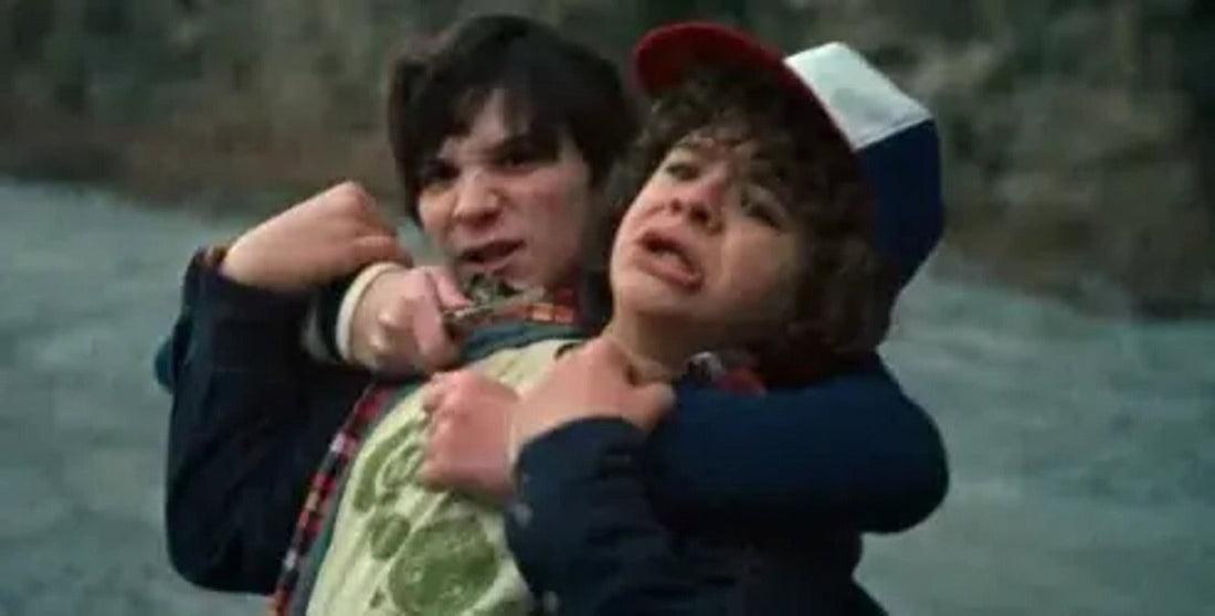 A schoolboy grips Dustin by the neck, above the quarry