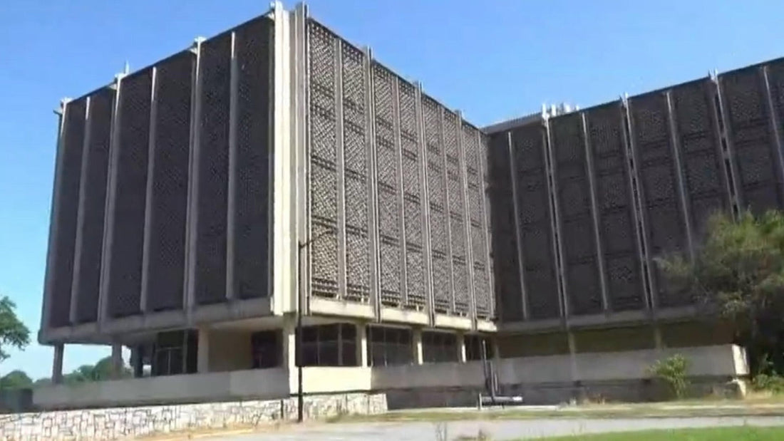 Large concrete school building, seen from the street, under a blue sky.