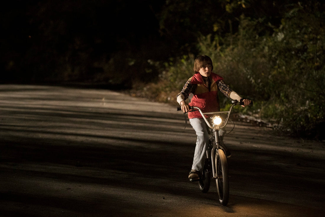 Will on a bike at night, on a tree-lined road, headlamp switched on.